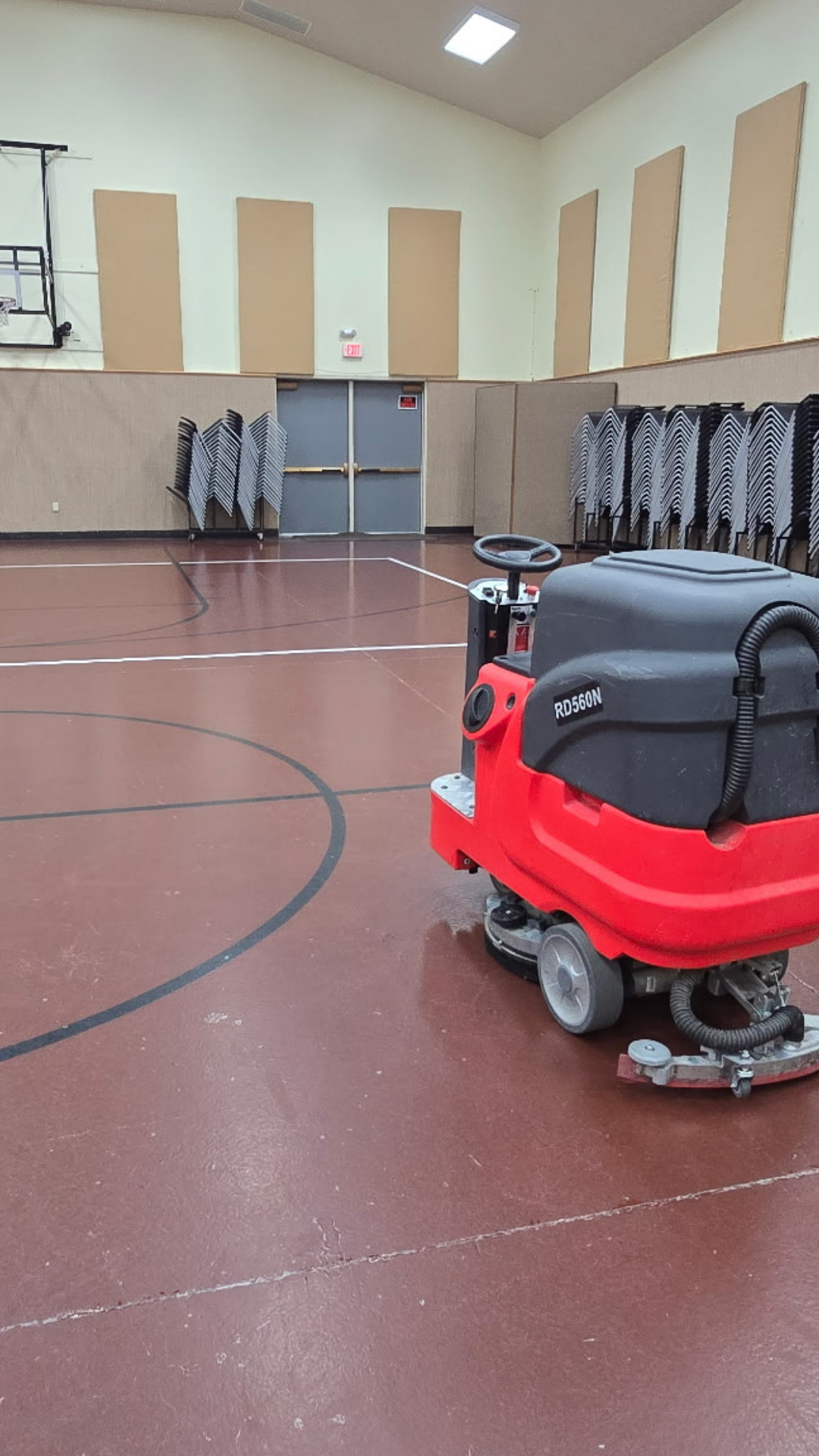 Red commercial floor scrubber parked on a gymnasium court