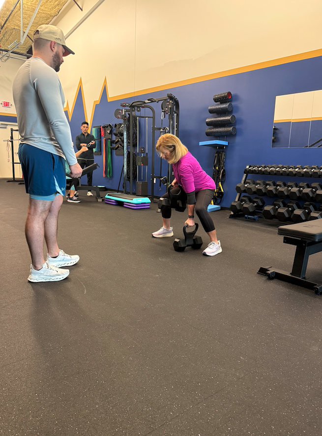 A trainer coaches a deadlift on the training floor at The Lab
