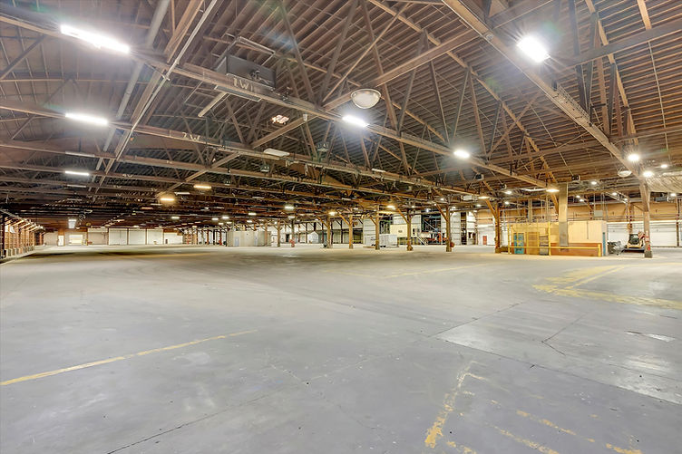Wide-angle interior view of Soundstage 01 with expansive concrete floor and exposed wooden truss ceiling