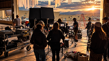 Behind the scenes at golden hour with crew and equipment inside an industrial production space