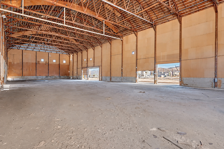 Expansive empty soundstage interior with vaulted timber truss ceiling and vertical wooden panel walls