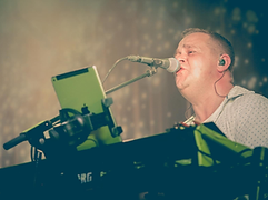 Sanger ved mikrofon og keyboard på scenen