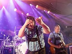 Musiker i lederhosen med tamburin på scenen