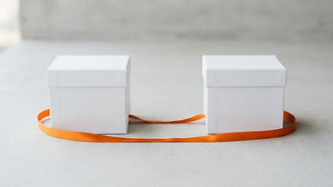 Two white gift boxes tied with an orange ribbon on a clean studio background
