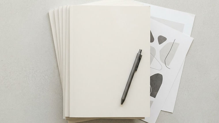 A collection of magazines with blank covers arranged with printed documents and a pen in an editorial setting