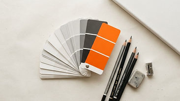 Organized creative tools including color fan decks, pens, and a blank drawing board with a prominent orange swatch.