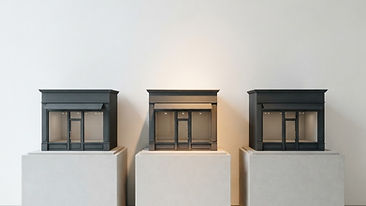 Three identical miniature online store interfaces displayed on stands, with one highlighted by warm accent lighting.