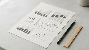 Abstract performance dashboard sheet featuring bar charts and line graphs, accompanied by a pen and ruler.