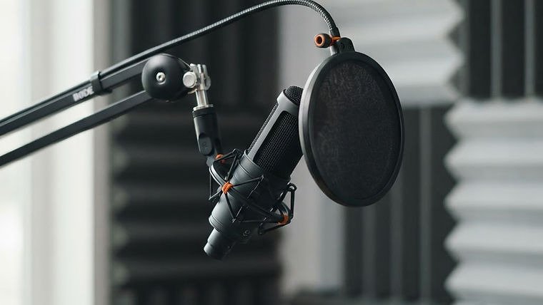 Studio microphone with a pop filter mounted on a boom arm in front of a soft soundproof wall