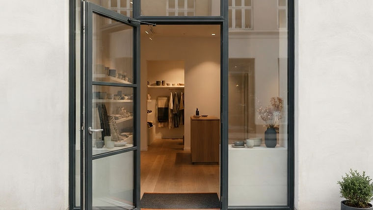 A warm and inviting storefront entrance with an open door and soft, natural lighting on a tidy welcome mat.