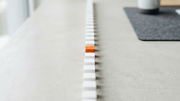 A row of white wooden blocks forming a path with a single orange block at the front