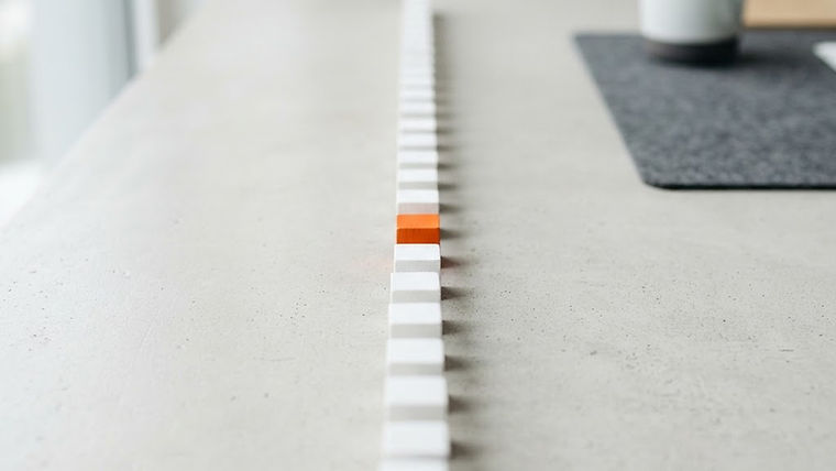 A row of white wooden blocks forming a path with a single orange block at the front