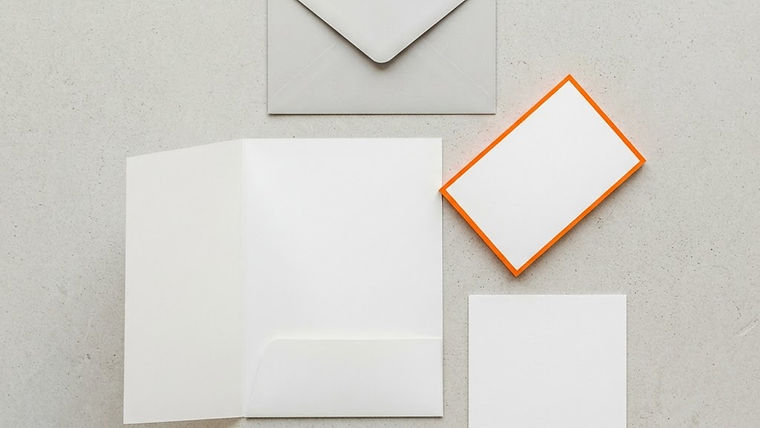 Blank visual identity papers neatly arranged on a light surface with an orange accent