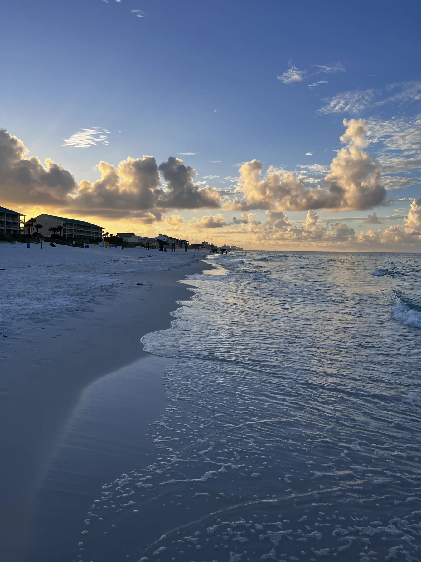 Golden clouds above a pale sandy beach and gentle surf