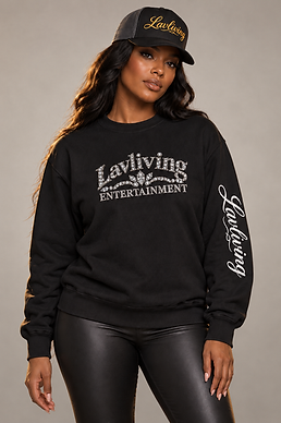 Woman wearing a black Lavliving jeweled crewneck and gold cursive trucker hat against a light neutral background, with her whole head and garment artwork visible.