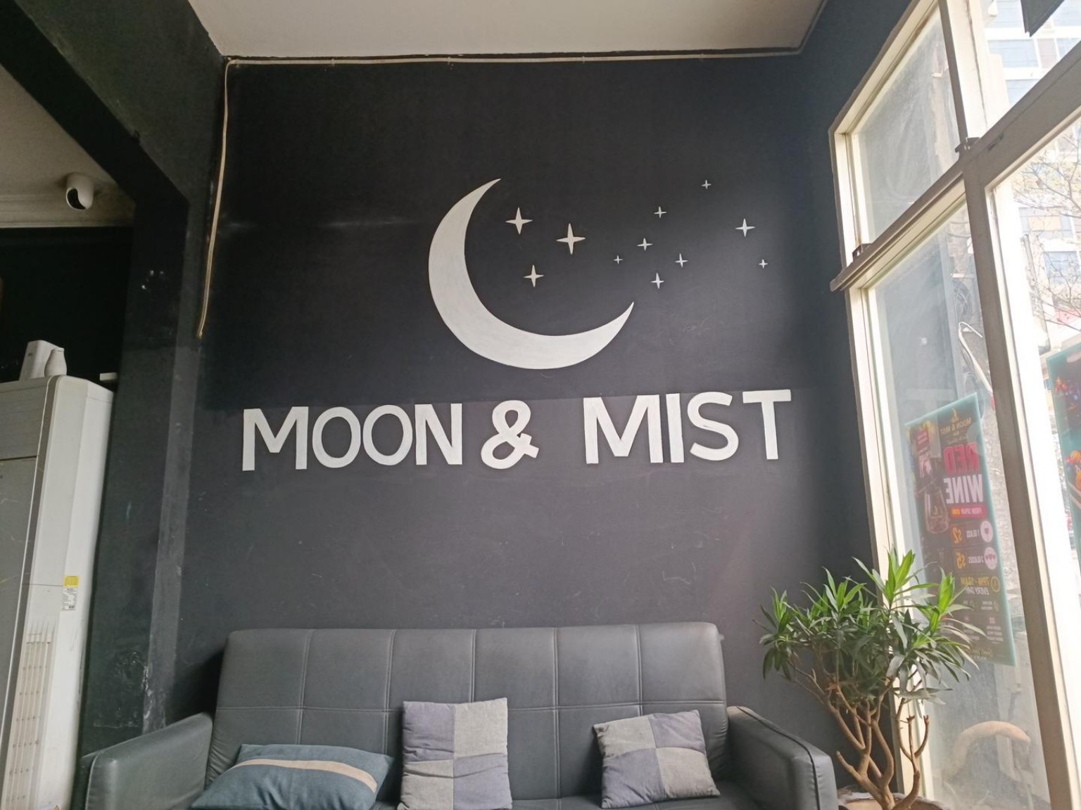 ספות אפורות ושלט Moon & Mist על קיר שחור עם סהר וכוכבים