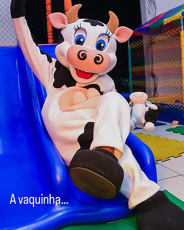Personagem vivo da vaquinha brincando no escorregador em festa infantil