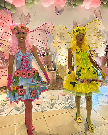 Recreadoras caracterizadas de fadas com asas iluminadas em festa infantil