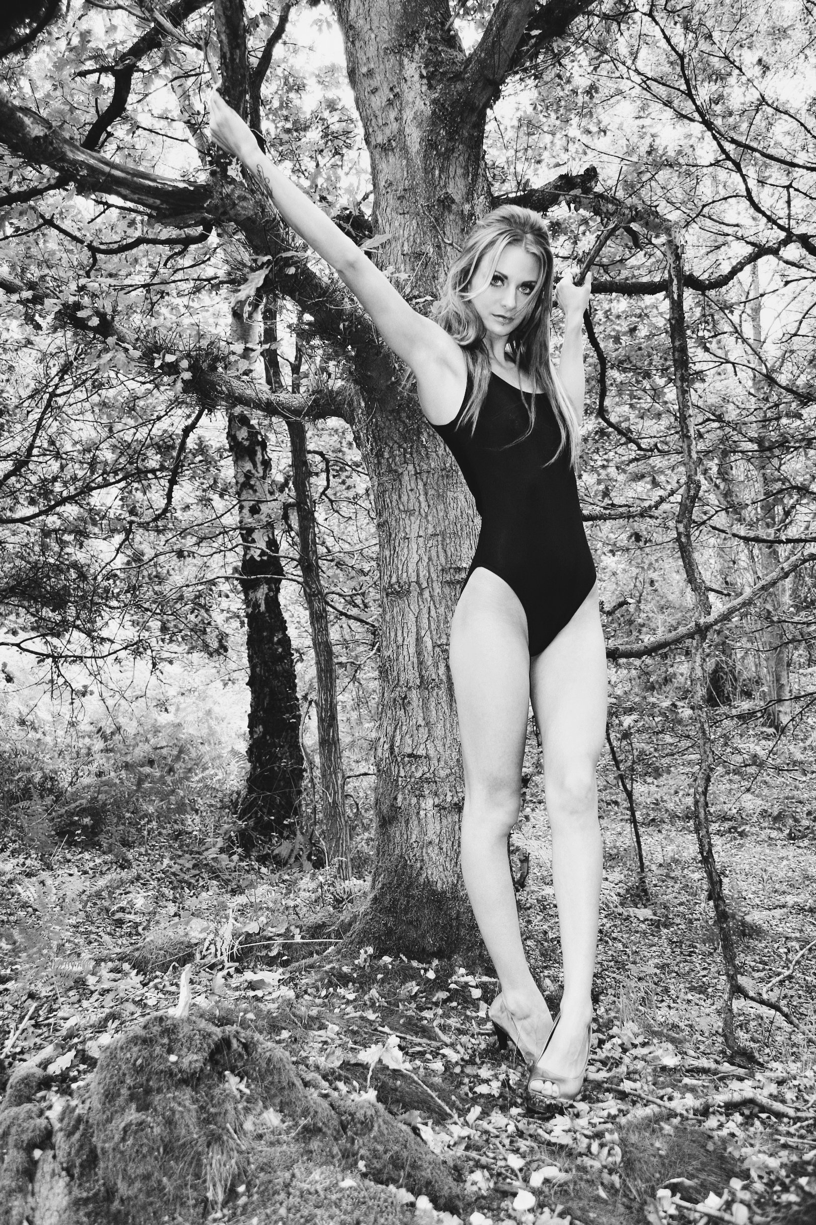 Woman in black bodysuit reaching for tree branch