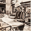 Rolled construction drawings, a scale rule and a hard hat on a concrete planning desk