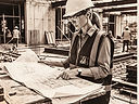 Rolled construction drawings, a scale rule and a hard hat on a concrete planning desk