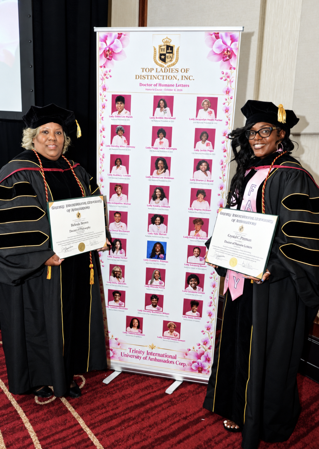 Two TIUAC doctoral honorees in regalia holding framed diplomas beside the Top Ladies of Distinction honorary degree banner