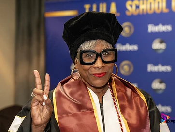 TIUAC humanitarian honoree in doctoral regalia with the gold HUMANITARIAN sash