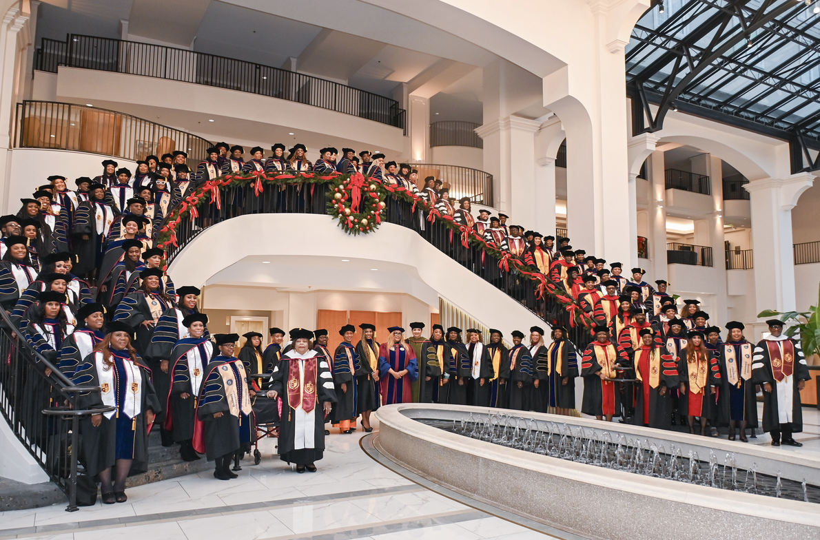A large gathering of TIUAC scholars in academic regalia on a grand decorated staircase