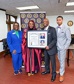 Dr. Adedayo Benjamins-Laniyi in a maroon academic gown with colleagues, holding her framed Honorary Georgia Citizen certificate from the Georgia Secretary of State