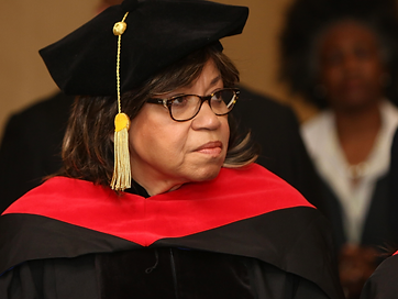 Portrait of a TIUAC graduate in doctoral tam and gown with gold tassel