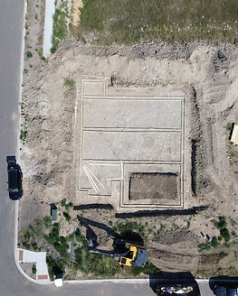 Aerial view of foundation footings on a corner lot in Bozeman, excavator and dumpster on site
