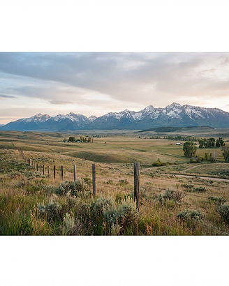 Open land and acreage in the Gallatin Valley, Montana with rolling fields and mountain ranges at dawn