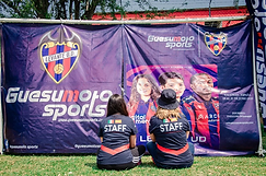 Staff del evento sentado frente al banner de Guesumoto Sports