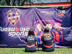 Staff del evento sentado frente al banner de Guesumoto Sports