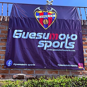 Banner de Guesumoto Sports con escudo del Levante UD sobre muro de ladrillo