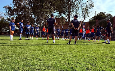 Grupo de jugadores en círculo con entrenadores del Levante UD en el campo