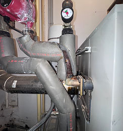Korrodierte Heizungsleitungen, verkalkte Pumpe und Manometer im Heizungsraum