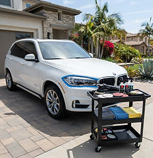 Mobile headlight restoration setup beside an SUV in a home driveway