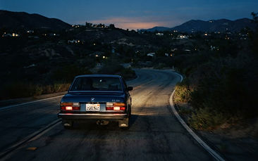 Car driving at night on a quiet road with dim, scattered headlight beams