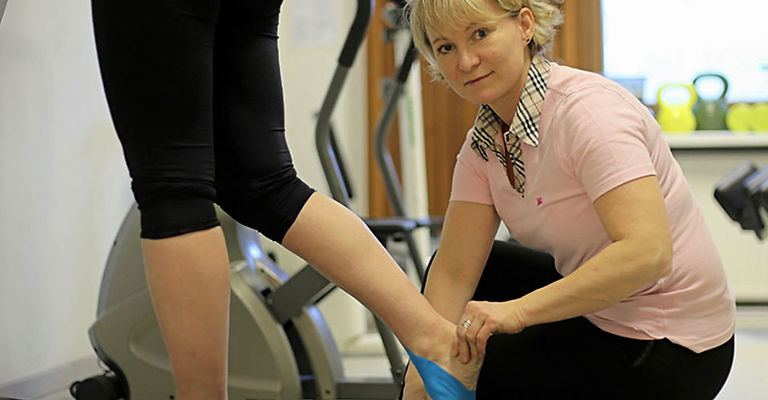 Fysioterapeutti Katja Kajas hoitotilanteessa asiakkaan kanssa kuntosalilla