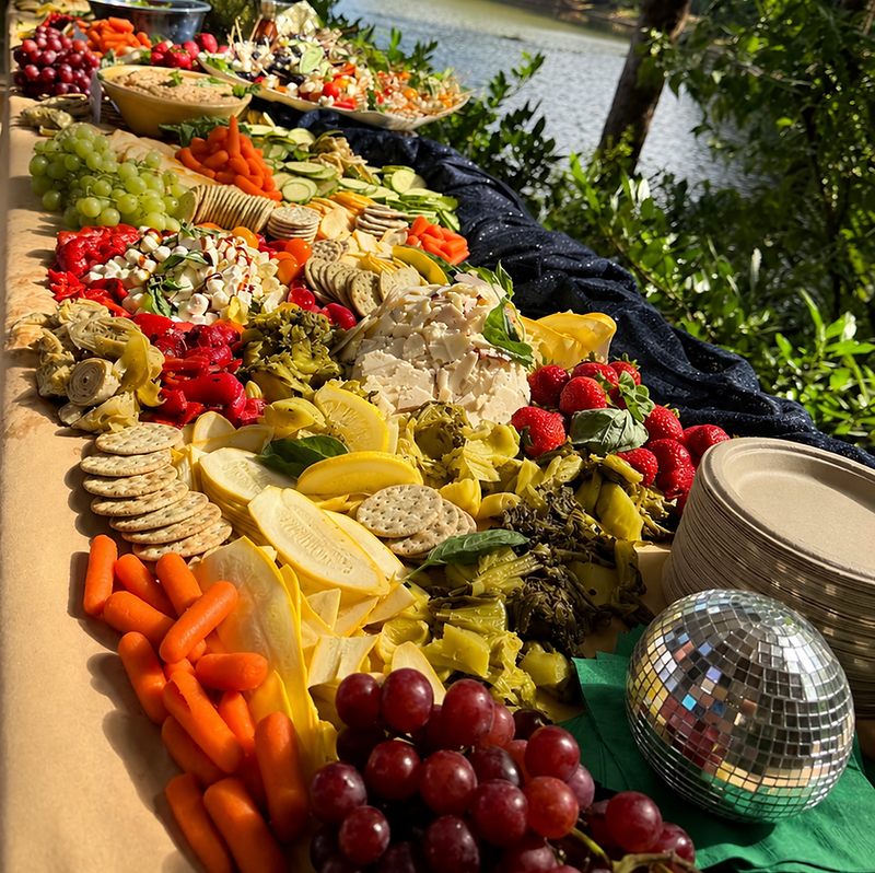 Lakeside grazing table spread with cheese, vegetables and fresh fruit