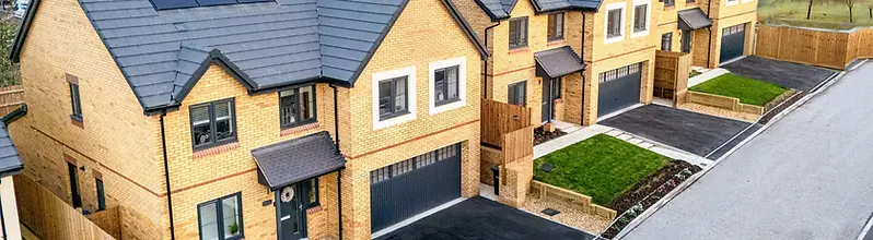A row of newly built Wain Homes, with buff brick frontages, driveways, garages and solar panels