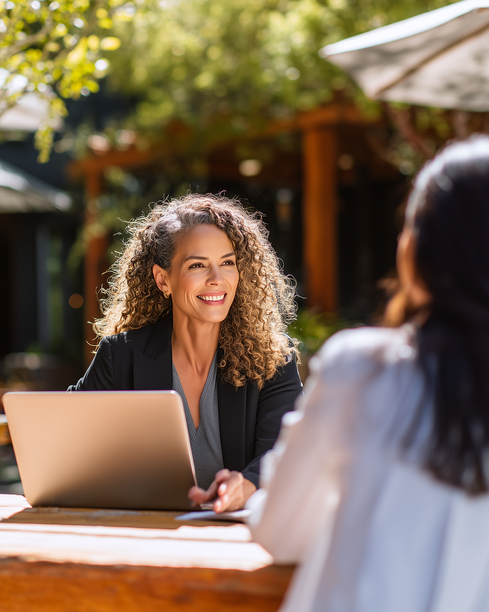 Presentation designer in conversation with a client at a sunlit outdoor table