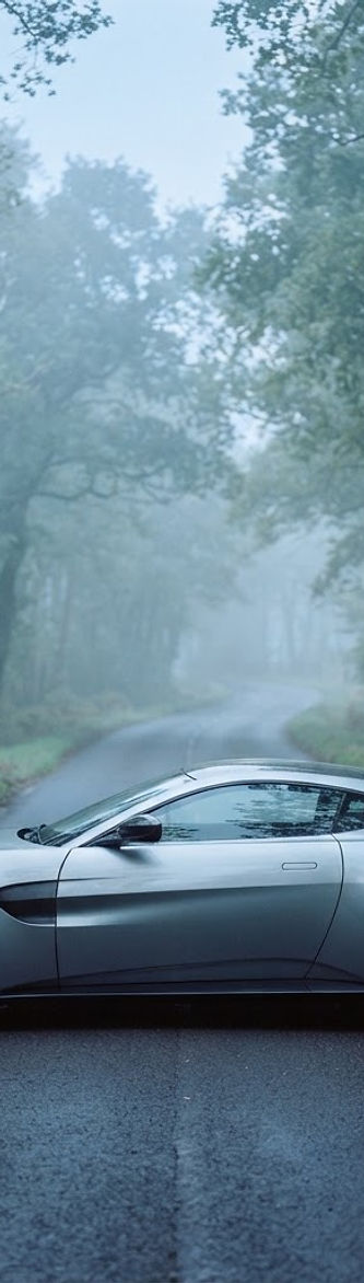 A prestige sports car on an empty country road at dawn