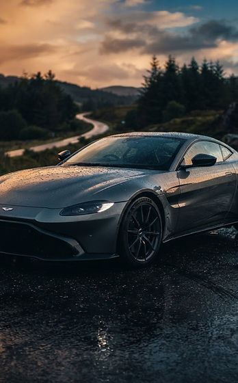 A sleek supercar on wet tarmac at golden hour