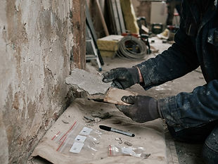 Schadstoffprüfung vor Umbau: Untersuchung von Baumaterialien: Handschuhe prüfen Materialproben, Probenbeutel und Etiketten daneben.