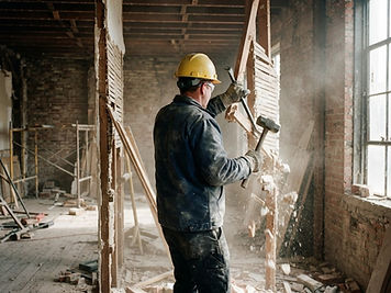 Abbruch & Rückbau: Ausbau einer Innenwand mit Brechstange und Vorschlaghammer, Ziegel und Holzbalken sichtbar.
