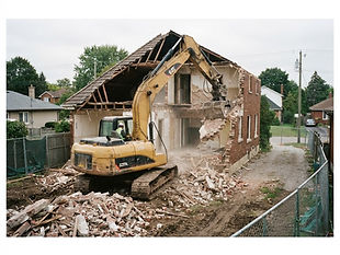 Rückbau Einfamilienhaus: Haus während des Abbruchs: Bagger reißt die Wand eines Einfamilienhauses ein, Schutt davor.