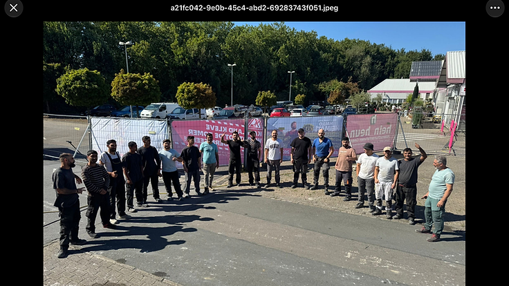 Team von Canova Group in Arbeitskleidung vor einem Bauzaun mit Bannern