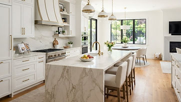 Remodeled kitchen with white shaker cabinets, marble island and pendant lights
